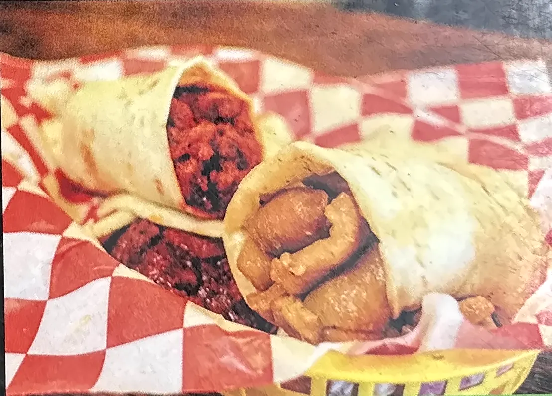 Two burritos in a basket lined with red and white checkered paper