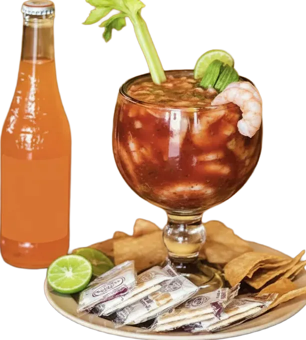 Shrimp cocktail in a tall glass with crackers and lime